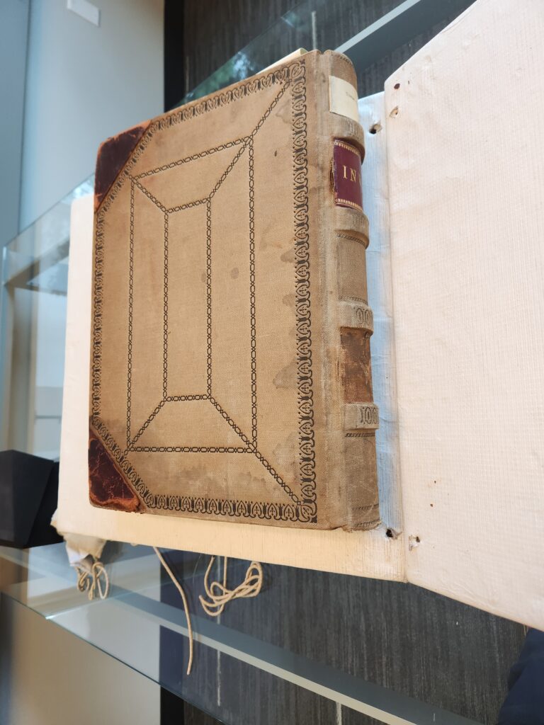 A large hardcover book in set on an archive's book cradle