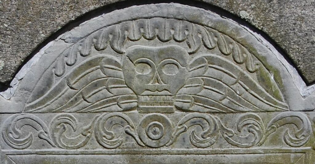 Gravestone carving of a winged skull